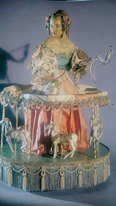 a statue of a woman on top of a carousel with horses and dogs around it