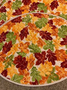 two round quilted placemats with autumn leaves on them sitting on the floor