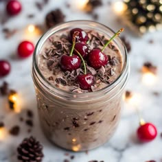 a jar filled with chocolate and cherries on top of a white table next to pine cones