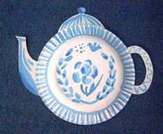 a blue and white teapot shaped plate with flowers on it's side, hanging from the wall