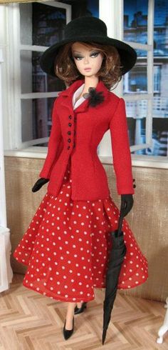 a doll wearing a red dress and black hat with polka dot print on the skirt