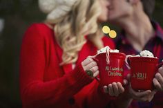 a man and woman kissing while holding mugs with the words all i want for christmas written on them