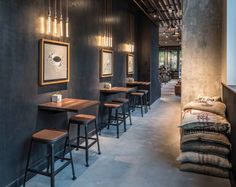 an empty restaurant with wooden tables and stools in the center, along with framed pictures on the wall