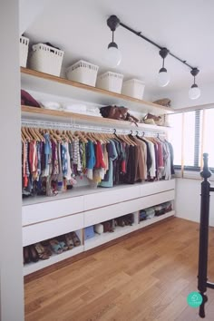 an organized closet with clothes and shoes on the shelves in front of a large window