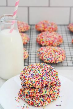 sprinkle covered cookies on a plate next to a glass of milk