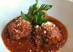 two meatballs covered in sauce and garnished with parmesan cheese