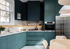 a kitchen with green cabinets and white counter tops, along with a wooden dining table