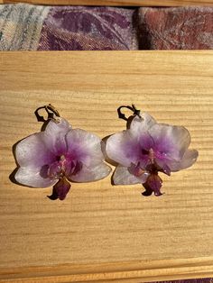 two purple flowers sitting on top of a wooden table