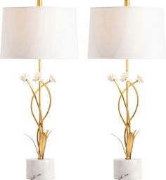 a pair of lamps with white flowers on each one and a marble base in the middle