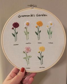 a hand is holding up a cross - stitch embroidery kit with flowers on it and the words grandma's garden