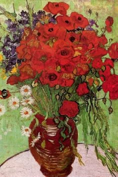 a vase filled with lots of red flowers on top of a white table next to a green wall