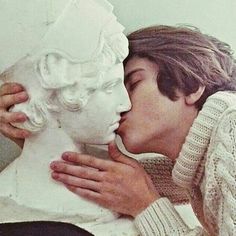 a man kissing a white statue with his face close to it's face,