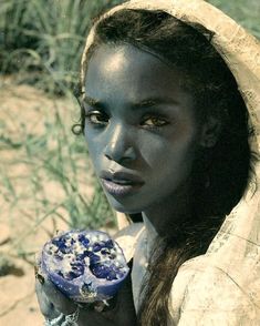 a woman holding a blue vase in her hand and looking at the camera with an intense look on her face