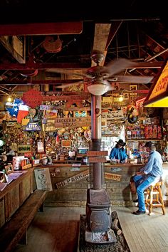 a man sitting on a stool in front of a wood stove inside of a store