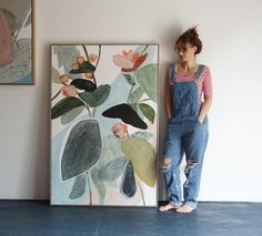 a woman standing next to a painting on the wall