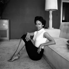 a black and white photo of a woman sitting on a couch in a living room