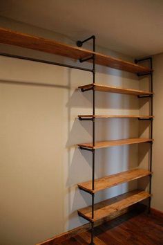 an empty room with wooden shelves and metal pipes on the wall, along with hard wood flooring