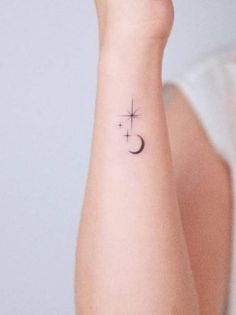 a woman's arm with a small cross and crescent tattoo on her left wrist