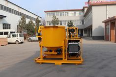 a large yellow machine sitting in the middle of a parking lot next to a building