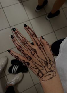 a woman's hand with black and white ink on it, in front of a tiled floor