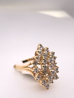 a yellow gold ring with white and clear stones on it's sides, sitting on a white surface