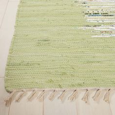 a green rug with fringes on the floor