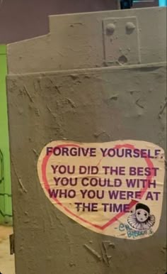 a sticker that is on the side of a pole near a wall with graffiti