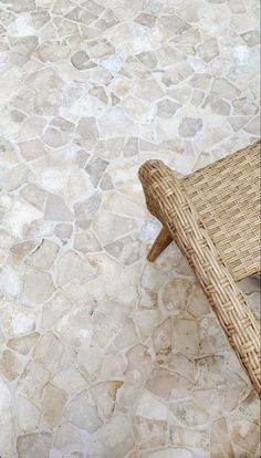 a wicker chair sitting on top of a stone floor next to a wooden bench