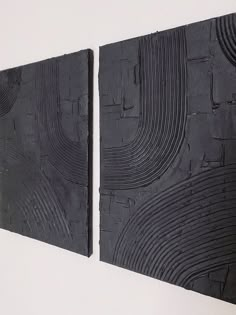 two pieces of black wood are hanging on the wall next to each other in an art gallery