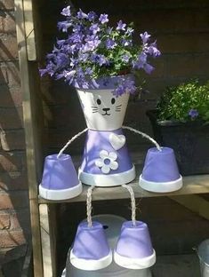 a purple and white flower pot sitting on top of a shelf next to blue shoes