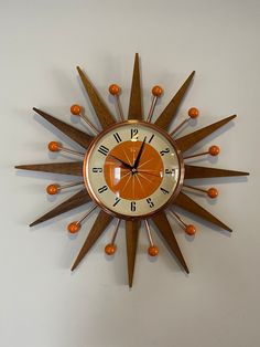 an orange and white clock mounted to the side of a wall with wooden stars on it