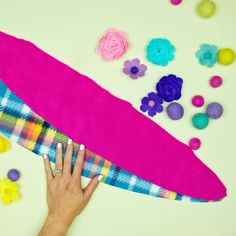 a person's hand on a towel surrounded by colorful felt flowers and other items