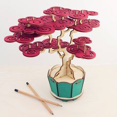 a small tree made out of paper with pencils next to it