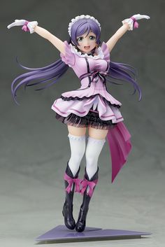 a figurine is posed on top of a purple platform with her arms outstretched