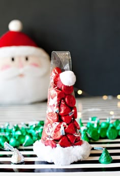 a santa clause candy bag sitting on top of a table next to green candies