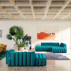 a living room filled with blue couches next to a potted plant and a painting on the wall