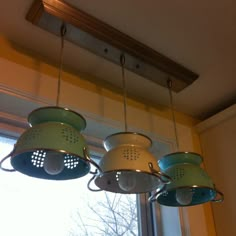 three green and white hanging lights in front of a window