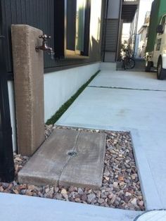 a concrete block sitting on the side of a building next to a sidewalk with gravel around it