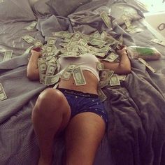 a woman laying on top of a bed covered in money