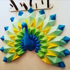 an origami peacock is hanging on the wall