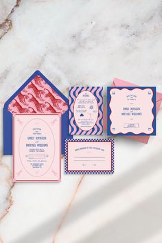 the wedding stationery is laid out on a marble table with pink and blue envelopes