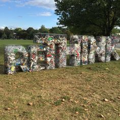 the word art is made out of trash cans and plastic bottles in front of a park