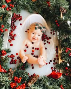 a baby in a bath surrounded by christmas decorations