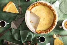 there is a pie on the table with cups and spoons