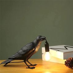 a black bird sitting on top of a wooden table next to a box with a light