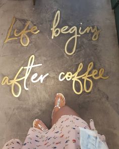 the feet of a woman standing in front of a sign that says life begins after coffee