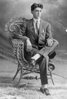 an old black and white photo of a man in a suit sitting on a chair