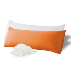 an orange and white pillow sitting next to a pile of rice