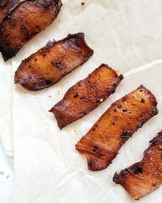 four pieces of meat sitting on top of a piece of wax paper next to each other