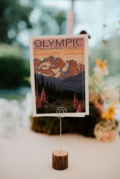 an olympic national park poster is displayed on a table in front of flowers and trees